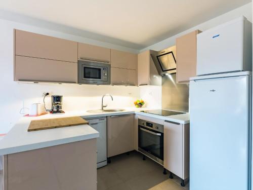 Il comprend une cuisine équipée d'appareils électroménagers blancs et d'un réfrigérateur blanc. dans l'établissement Apartment La Chênaie-5 by Interhome, à Saint-Aygulf