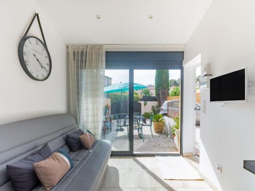 un salon avec un canapé et une horloge au mur dans l'établissement Apartment l'orée de boulouris by Interhome, à Saint-Raphaël