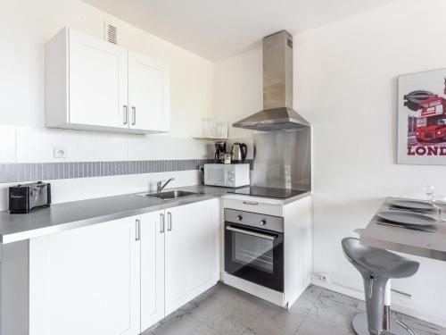 cocina con armarios blancos, fregadero y fogones en Apartment Le Cormoran by Interhome, en Le Lavandou