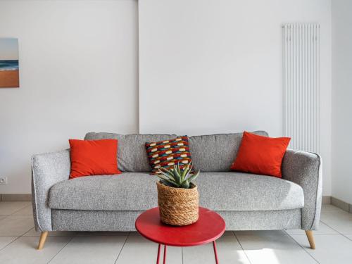 a gray couch with orange pillows and a red table at Apartment Les Villas du Men Du-2 by Interhome in Carnac
