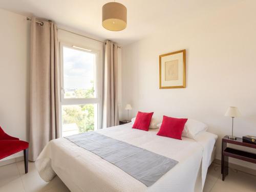 une chambre avec un lit avec des oreillers rouges et une fenêtre dans l'établissement Apartment bel horizon by Interhome, à Cagnes-sur-Mer