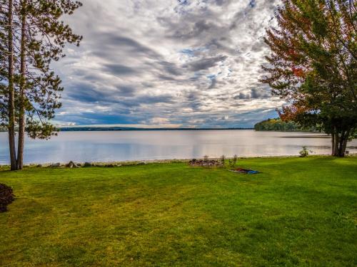 a grassy area with a view of a lake at The Maine Lake House with an Amazing Sand Beach! in Unity