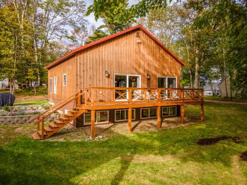 a large wooden house with a large deck at The Maine Lake House with an Amazing Sand Beach! in Unity