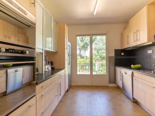 une grande cuisine avec des placards blancs et une grande fenêtre dans l'établissement Apartment Le Roumanille by Interhome, à Saint-Aygulf