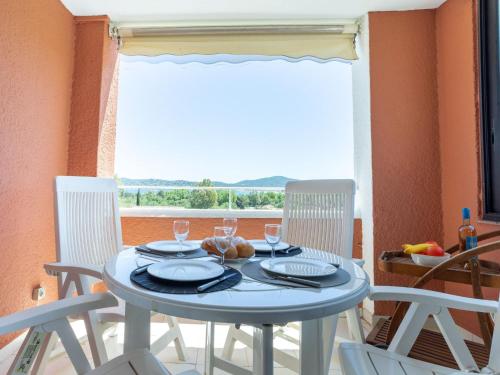 - une table avec deux chaises et une table avec des verres à vin dans l'établissement Apartment Les Parcs de Grimaud by Interhome, à Grimaud