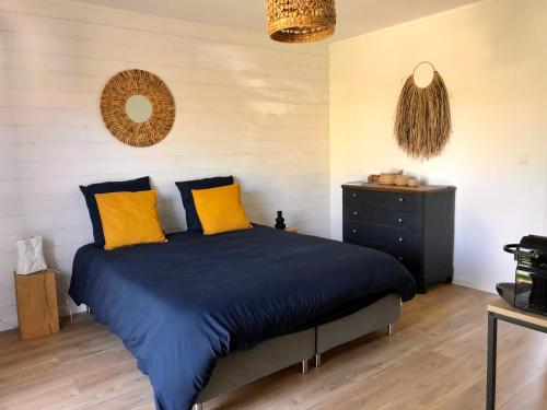 um quarto com uma cama com lençóis azuis e almofadas amarelas em Agréable suite - Bassin Arcachon em Le Teich