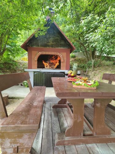 a picnic table and a fireplace on a wooden deck at Holiday House Trnovac in Trnovdc