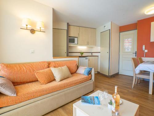 un salon avec un canapé orange et une cuisine dans l'établissement Apartment L'Esquinade FH 003 by Interhome, à Agay