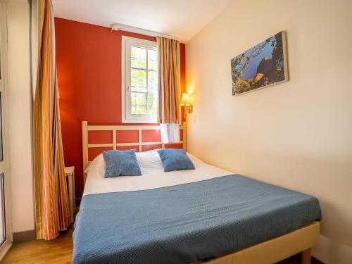 Cette petite chambre comprend un lit avec des oreillers bleus. dans l'établissement Apartment L'Esquinade FH 003 by Interhome, à Agay