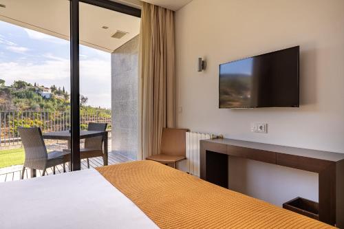 a hotel room with a bed and a flat screen tv at Monchique Resort & Spa in Monchique
