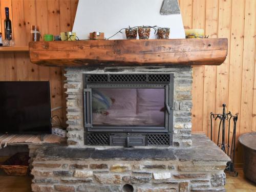 a living room with a stone fireplace with a tv at Apartment Nido dello Stelvio by Interhome in Pezzo