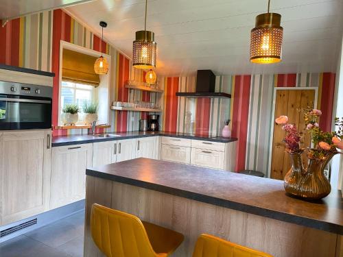 eine Küche mit einer Theke mit gelben Stühlen in der Unterkunft Holiday Home Wiringherlant-11 by Interhome in Hippolytushoef
