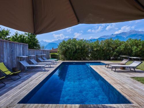 a swimming pool with lounge chairs and an umbrella at Villa Woodhouse by Interhome in Colico