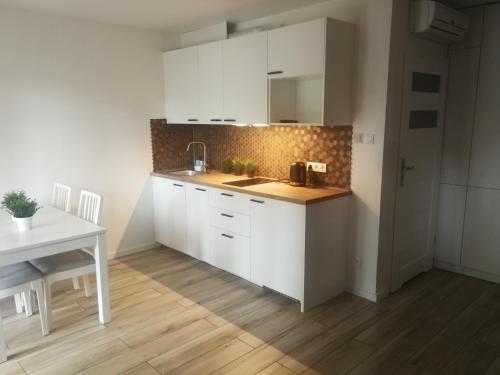 a kitchen with white cabinets and a wooden floor at Apartament Rodzinny Baltic Park Stegna in Stegna