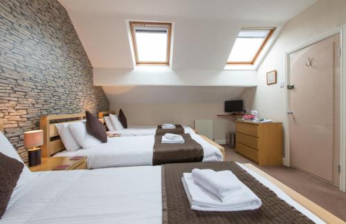 a bedroom with two beds and a brick wall at Thornbank House (incl off-site health club) in Windermere