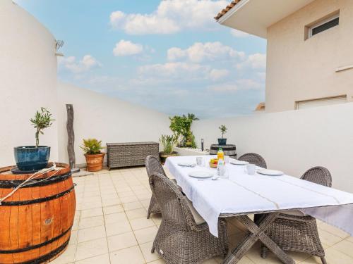 d'une terrasse avec une table, des chaises et un tonneau. dans l'établissement Apartment Le Nadir-4 by Interhome, à Fréjus