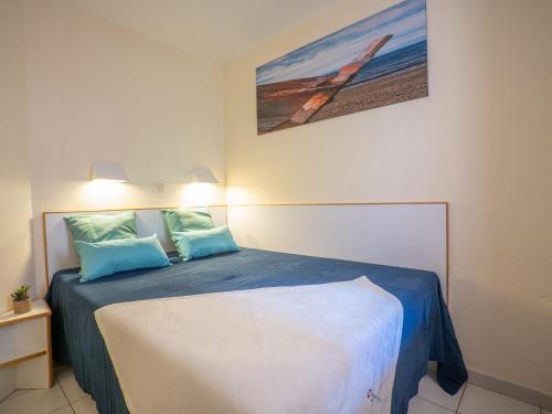 - une chambre dotée d'un lit avec des draps bleus et un tableau dans l'établissement Apartment L'Esquinade - G4 125 by Interhome, à Agay