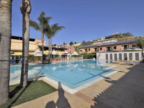 a large swimming pool with palm trees and buildings at Apartment L'Ancora-2 by Interhome in Porto Empedocle