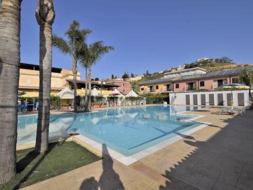 Una gran piscina con palmeras y edificios. en Apartment L'Ancora-2 by Interhome, en Porto Empedocle