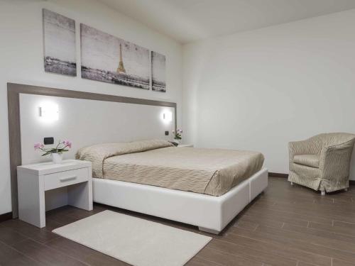 una camera bianca con un letto e una sedia di Ferrari Hotel a Carugate
