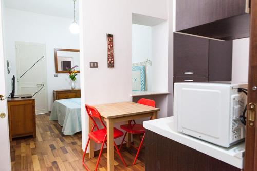 una pequeña cocina con mesa y sillas rojas en Santa Restituta in Cagliari Centre Q4825, en Cagliari