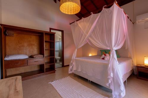 a bedroom with a canopy bed and a mirror at Casa Villa Cristian Pé na Areia in Arraial d'Ajuda