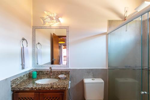 a bathroom with a sink and a mirror and a toilet at Casa Villa Cristian Pé na Areia in Arraial d'Ajuda