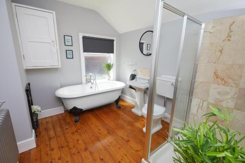 a bathroom with a tub and a toilet and a sink at Large Derby Cathedral Town House - Sleeps 8 w parking in Derby