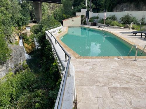 a swimming pool with a fence next to a river at MOULIN DE L'OULETTE in Soubès