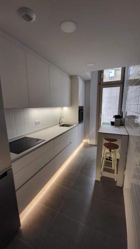 une cuisine avec des placards blancs et un comptoir avec un tabouret dans l'établissement Apartamento Palacio de los Toledo, à Corella