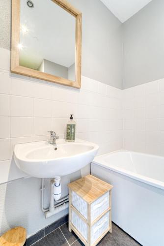 une salle de bain avec un lavabo, une baignoire et un miroir dans l'établissement Mon Rez-de-Chaussée Ville Parking Privé Un-Séjour-à-Part, à Metz