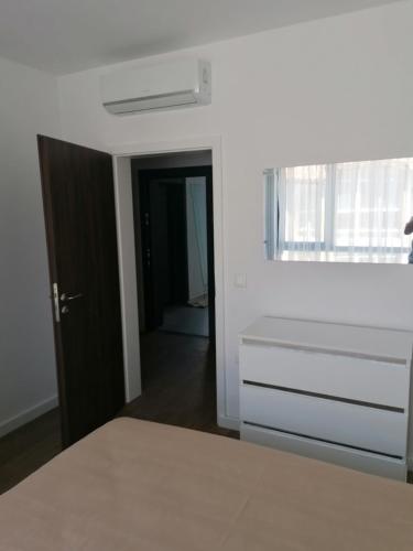 a white bedroom with a bed and a window at Apartament Kali in Ahtopol