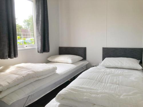 two beds sitting in a room with a window at Chalet 579 op Recreatiepark De Wielen in Sint Maarten
