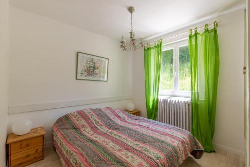 a bedroom with a bed and a window with green curtains at Appartement Mont Colombier in Trévignin