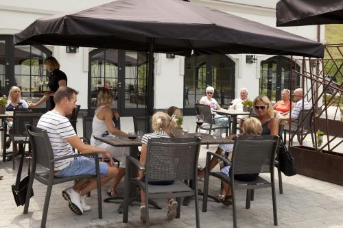 a group of people sitting at tables under an umbrella at Hotel Pałac Jugowice in Wałbrzych