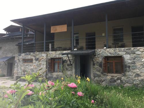 a stone building with a balcony and flowers at Hotel Lemi in Mestia