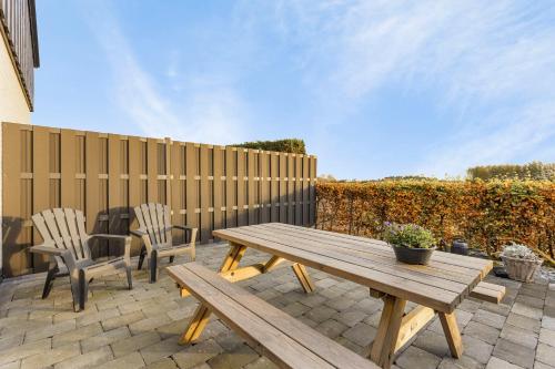 a wooden picnic table and two chairs on a patio at Wolfsveld - dicht bij strand en duinen! in Castricum