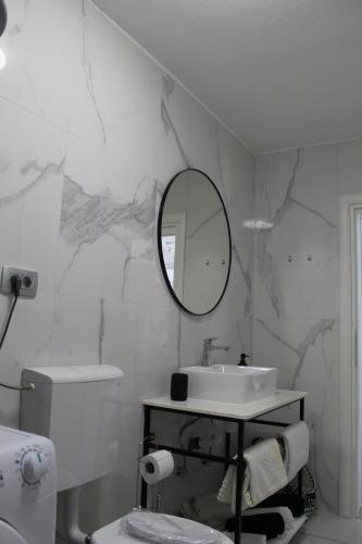 La salle de bains blanche est pourvue d'un lavabo et d'un miroir. dans l'établissement Apartment River, à Klis