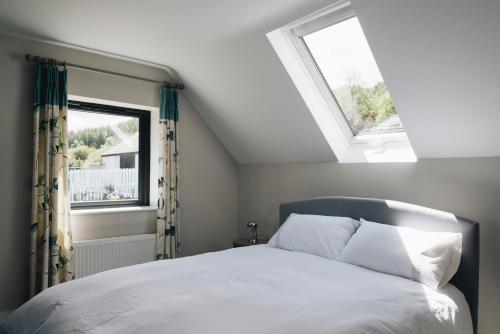 a bedroom with a bed and two windows at Lamb Cottage in Ballycastle