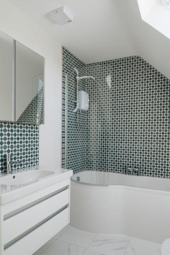 a white bathroom with a tub and a sink at Lamb Cottage in Ballycastle