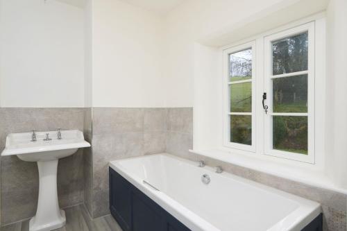y baño con bañera blanca y lavamanos. en 1 Lower Spire, en Dulverton
