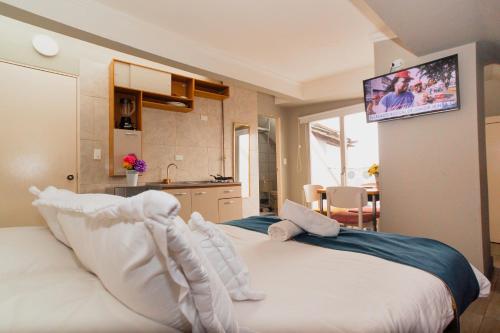 a bedroom with a white bed with a tv on the wall at ApartaSuites & Hotel Bogota Suamox in Bogotá