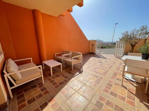 a patio with chairs and tables and a wall at El Alamillo ground floor apartment with sea view in Mazarrón