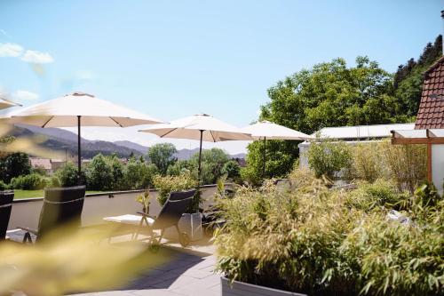 a patio with umbrellas and chairs with a view at Am Rain - Natur und Spa in Winden im Elztal