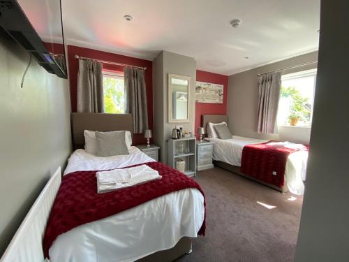 two beds in a room with red walls at The Beeches, Ashby-de-la-Zouch in Ashby de la Zouch