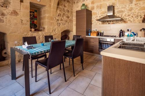 een keuken met een tafel met stoelen en een wastafel bij 250 yo Tal-Bambinu Farmhouse in Xagħra