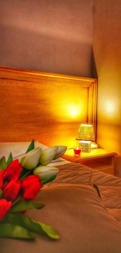 a bedroom with a bed with a vase of red flowers at Casina Raho B&B in Nardò
