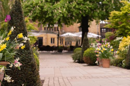 a garden with flowers and trees and a building at The Lygon Arms - an Iconic Luxury Hotel in Broadway