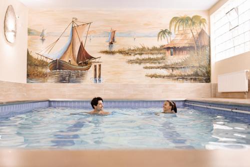 two people in a swimming pool with a painting at Wellness Pension am Rain in Winden im Elztal