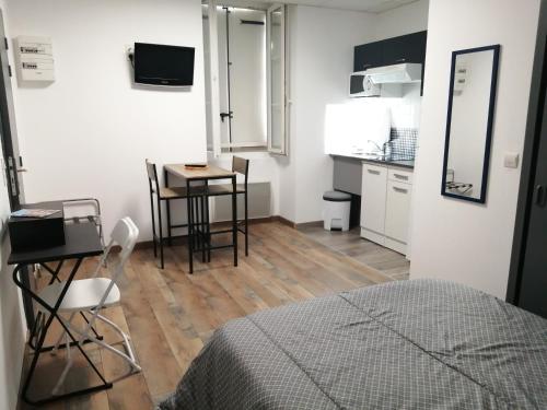 1 dormitorio con cama, mesa y cocina en 2 appartements au choix centre ville de Souillac entre Sarlat et Rocamadour, en Souillac